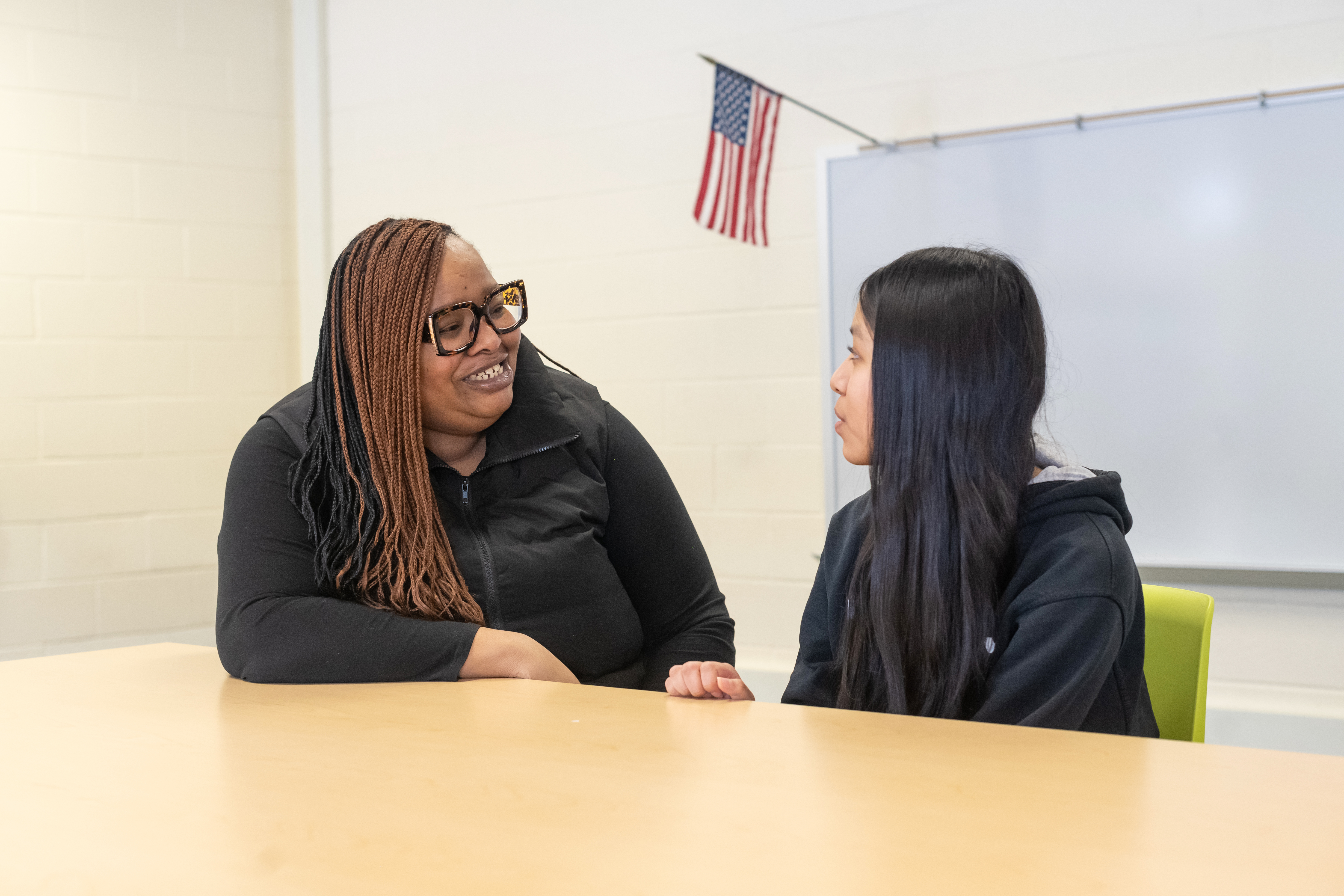 A woman, left, smiles as she talks to a girl, right.